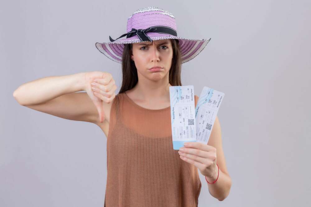 Una mujer enfadada posa con sus billetes de avión. aerolínea. Foto: Freepik.