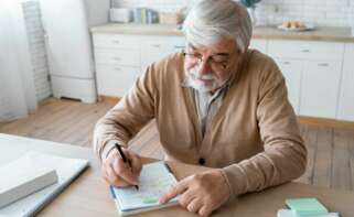Un beneficiario de una pensión de jubilación hace unas anotaciones en una libreta. Foto: Freepik,
