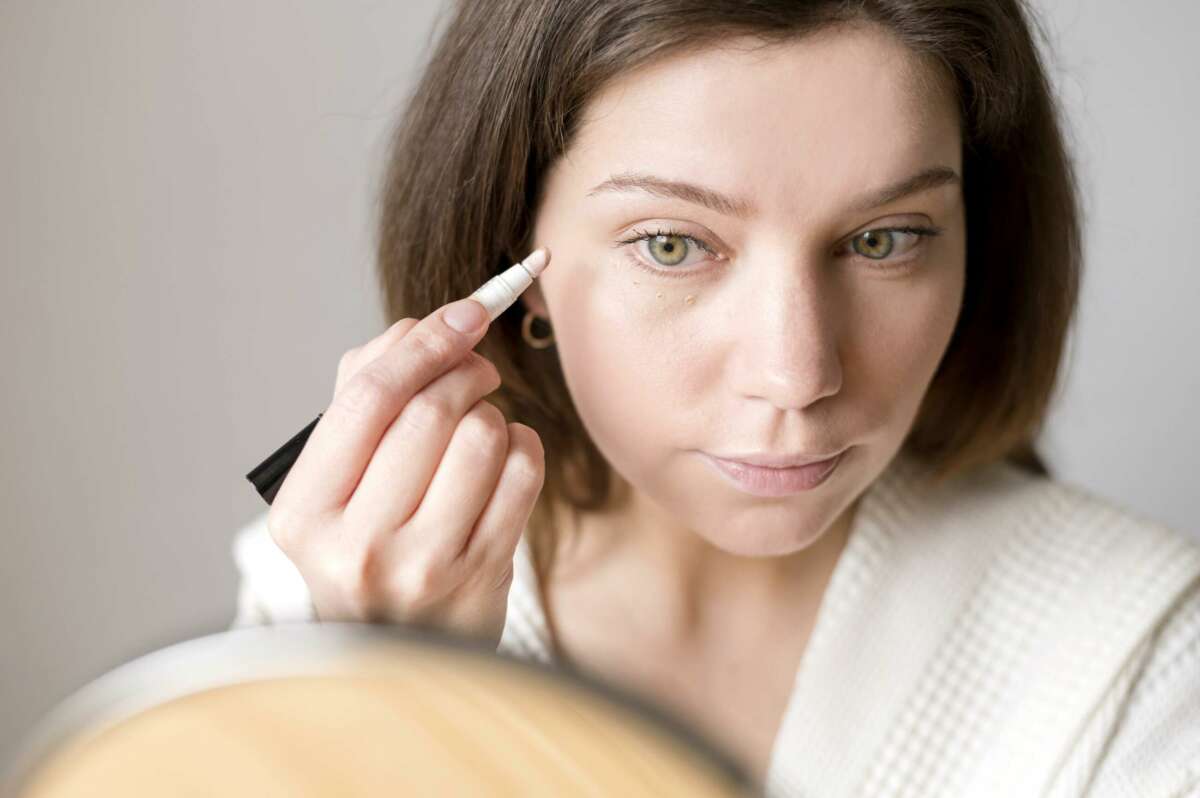 Una mujer se aplica corrector de maquillaje