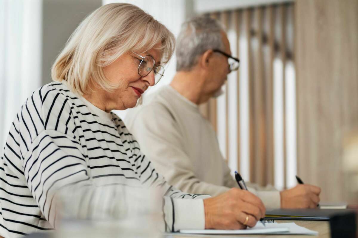 Dos jubilados realizan cálculos en un papel para contratar una renta vitalicia. Foto: Freepik.