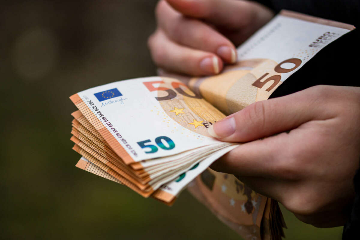 Una persona cuenta billetes de 50 euros. unicaja. Foto: Freepik.