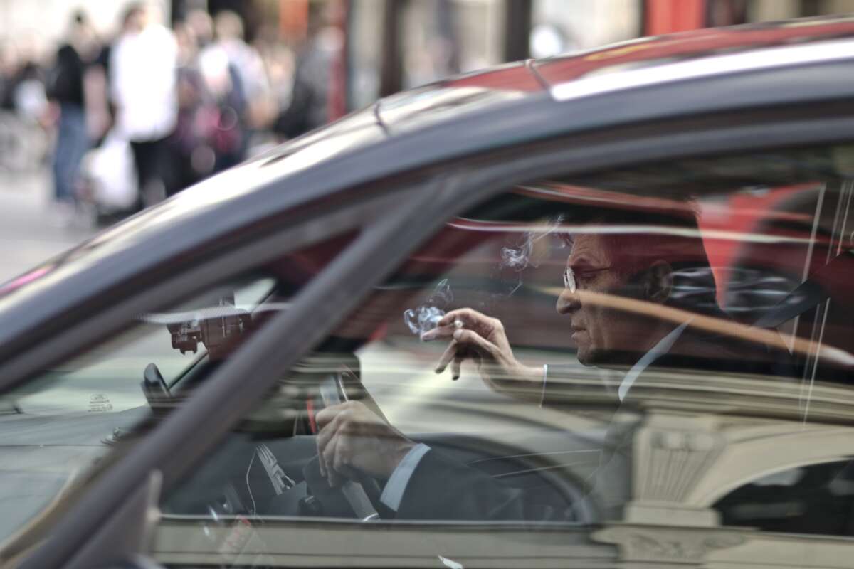 Un conductor fuma en su vehículo. carnet. Foto: Freepik.