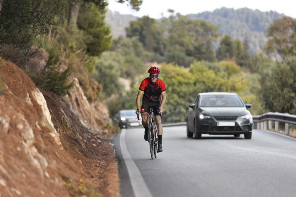 Un hombre conduce su bicicleta por la carretera. Foto: Freepik.