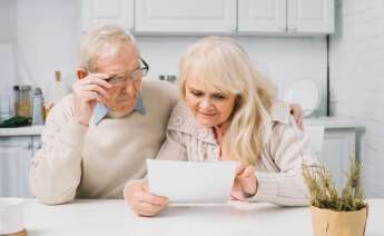 Unos abuelos consultan un documento. jubilación.