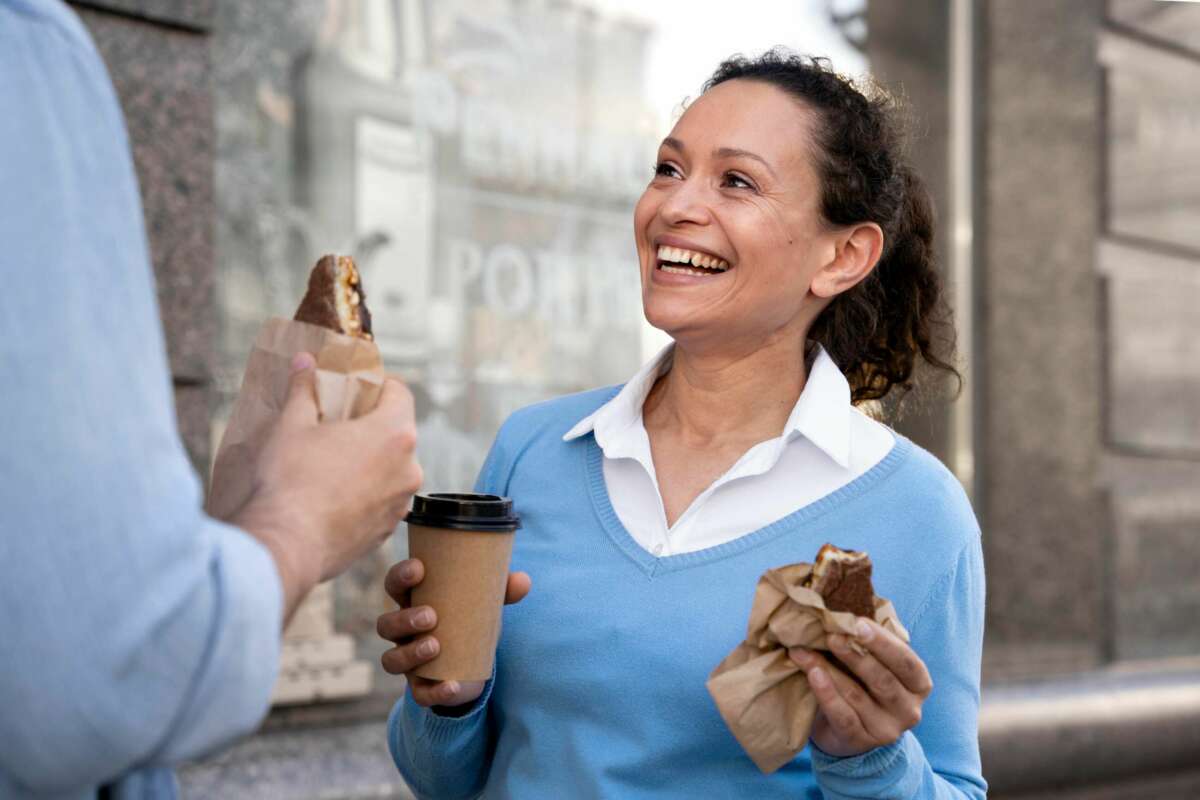 Una mujer se bebe un café mientras sostiene un dulce. BBVA. Foto: Freepik.