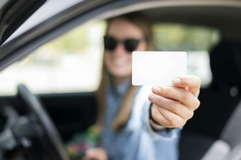 Una chica sostiene su carnet de conducir.