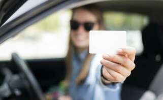 Una chica sostiene su carnet de conducir.