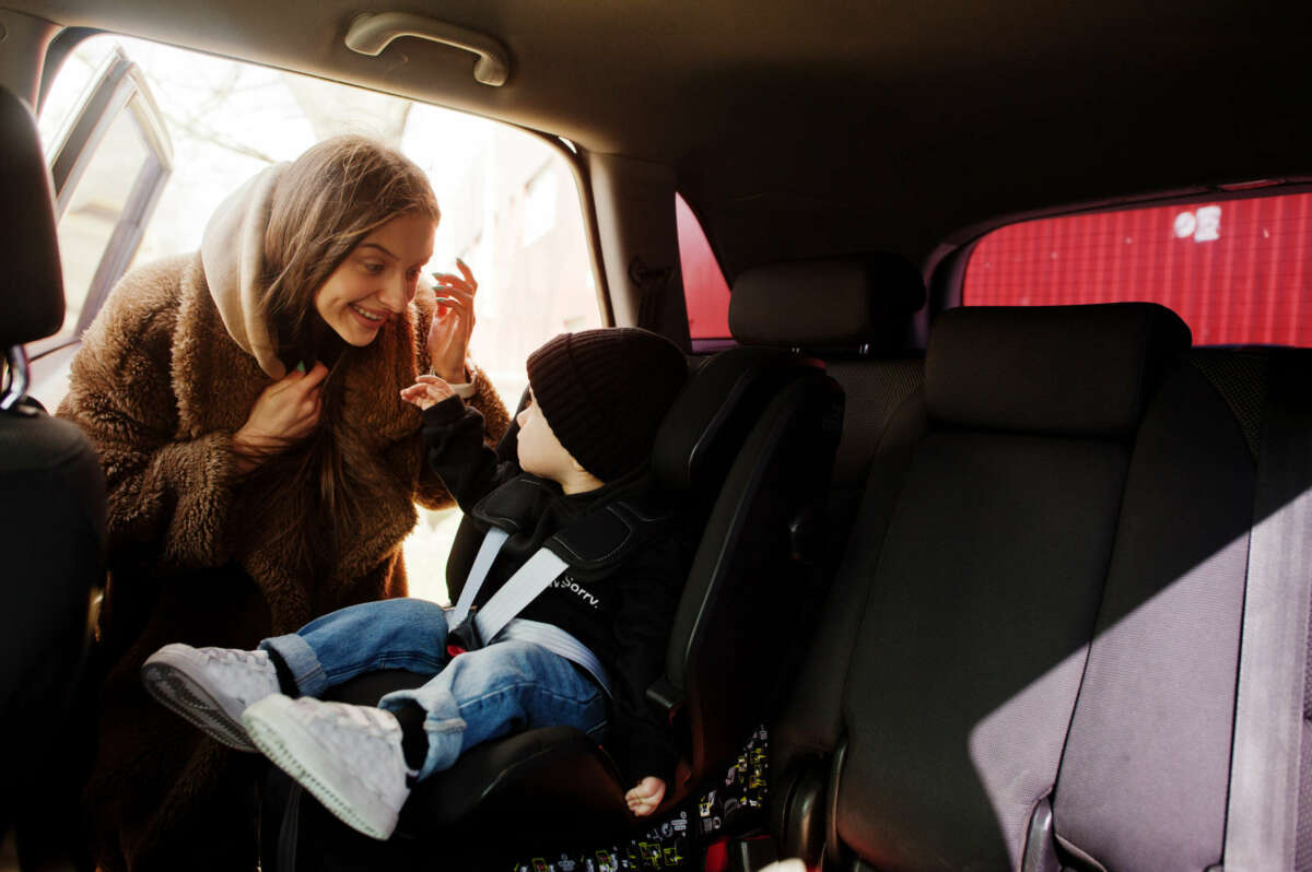 Una madre y su bebé, en una sillita para bebés en el coche.