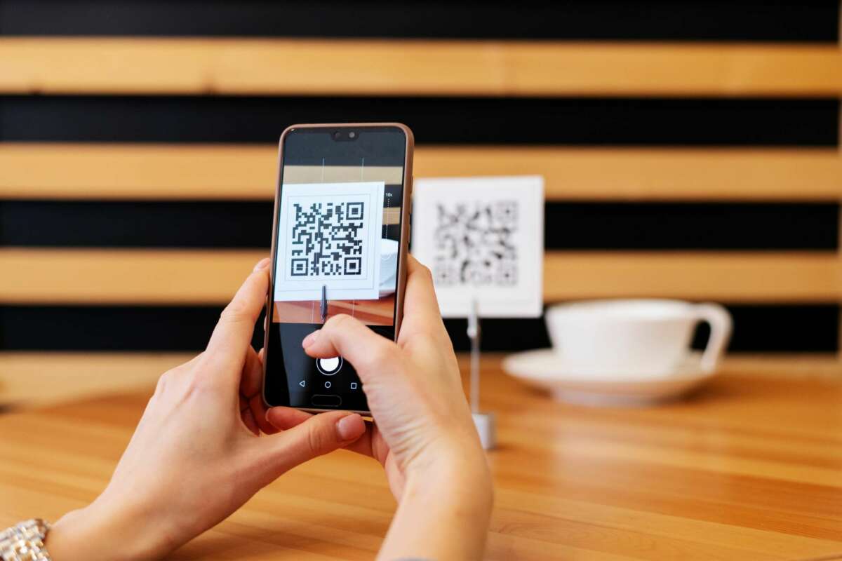 Una mujer escanea una código QR-. EVO Banco. Foto: Freepik.