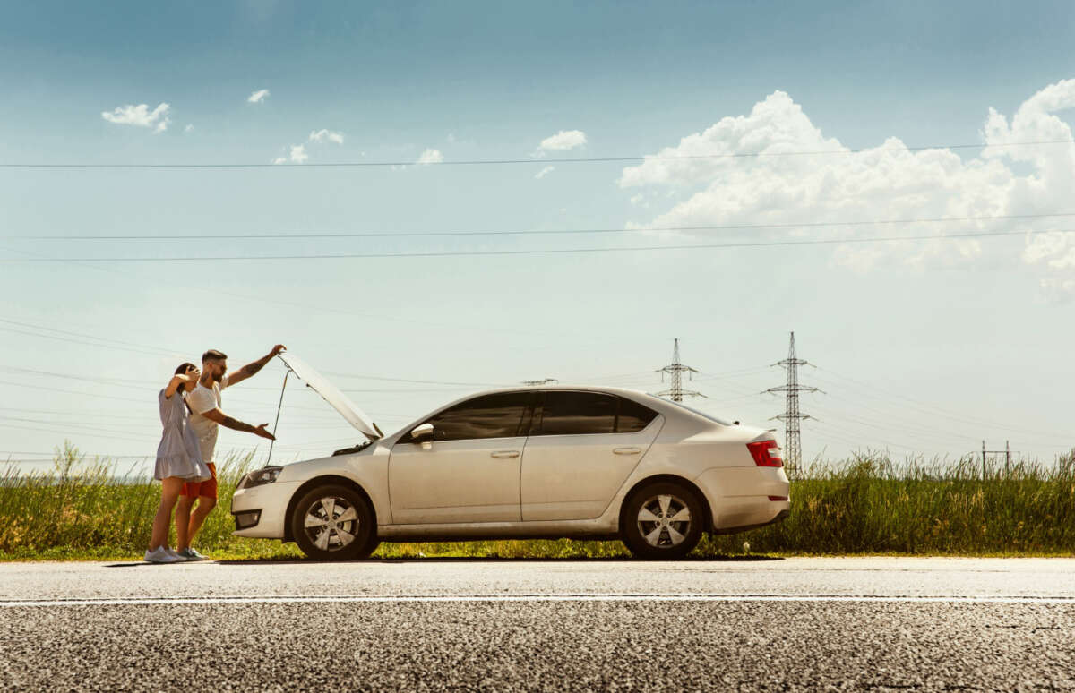 Una pareja con un coche en la carretera.