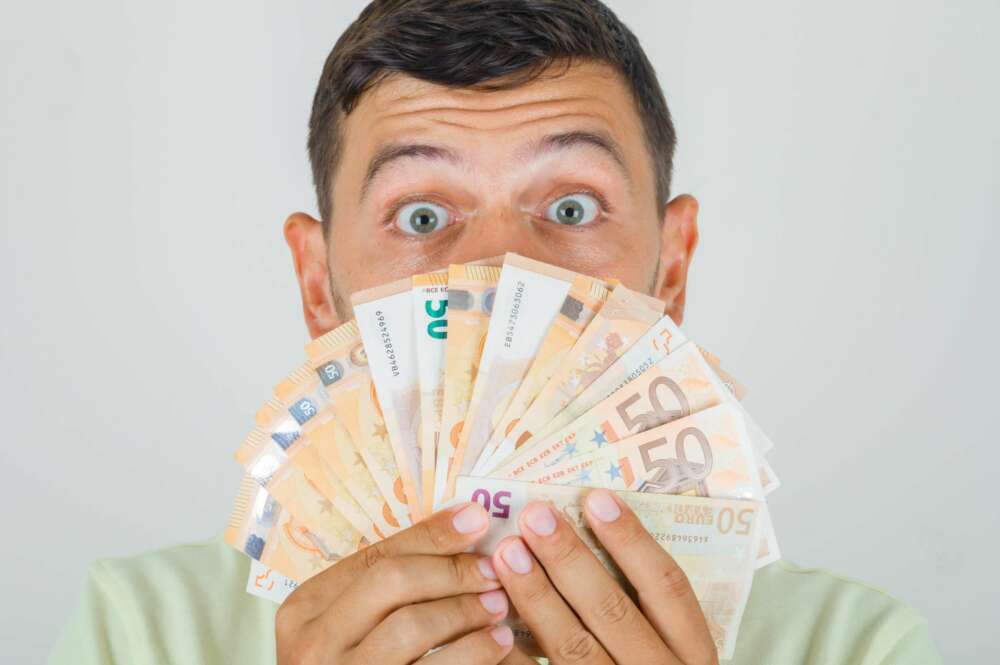 Un hombre sostiene unos billetes de 50 euros. Foto: Freepik.