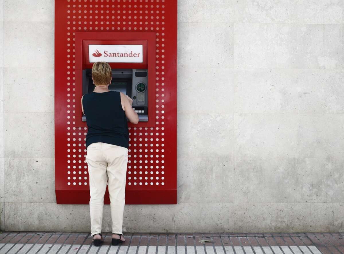 Una mujer saca dinero de un cajero automático. Foto: Banco Santander.