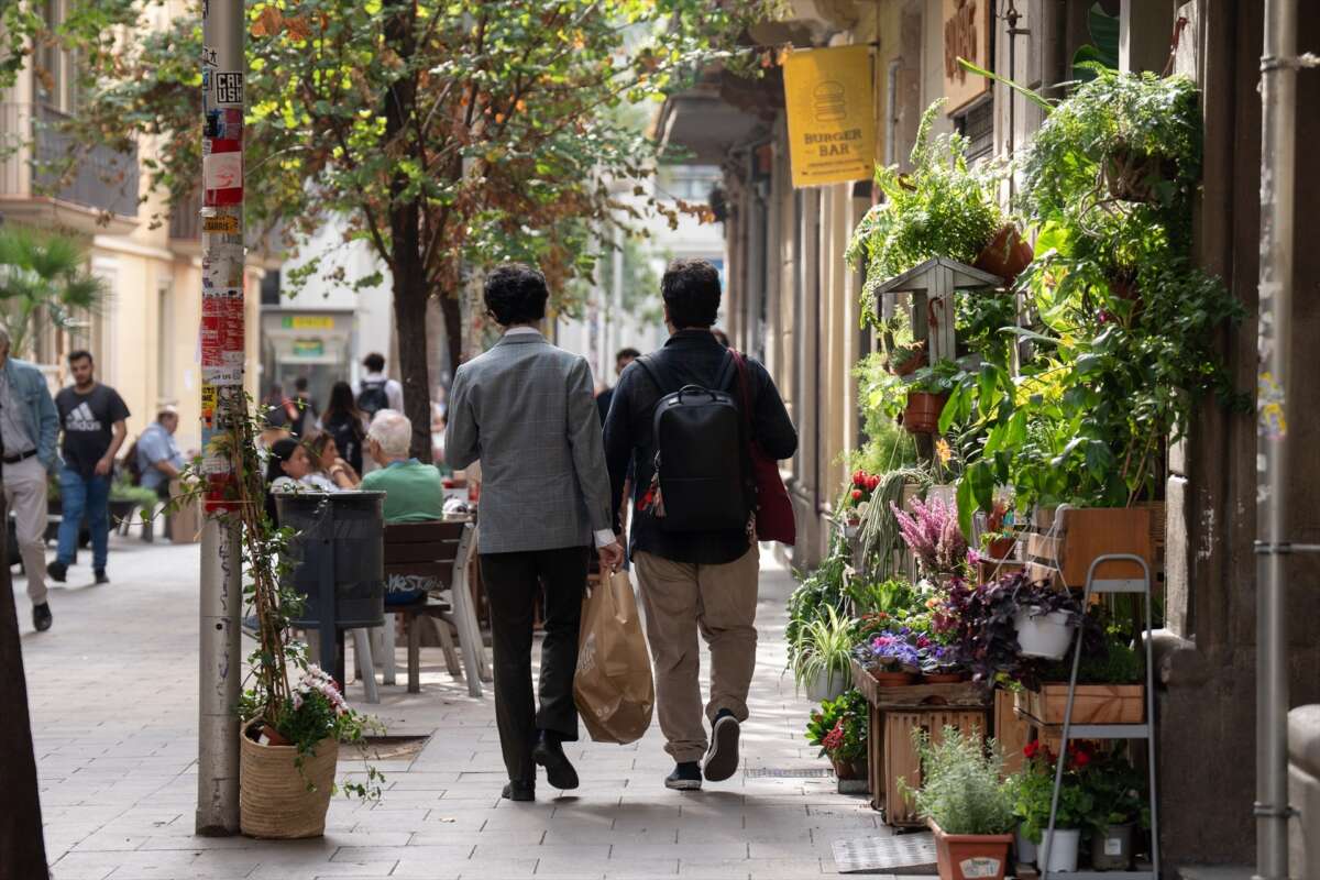 Dos jóvenes pasan al lado de un comercio, en Barcelona. Foto: David Zorrakino / Europa Press