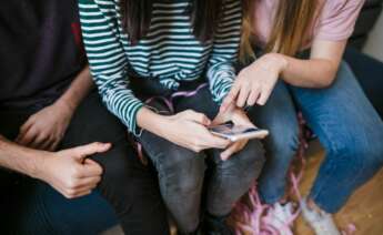 Personas viendo un teléfono móvil | Foto de Servimedia