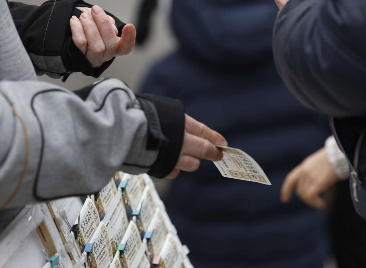 Una personas compra un décimo de lotería de Navidad a una vendedora ambulante.