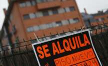 Un papel de alquiler pegado en un verja con un edificio desenfocado de fondo