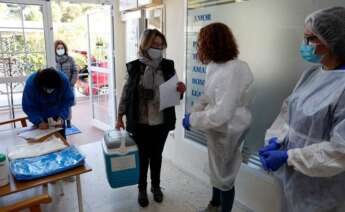 Una trabajadora de la consellería de Sanidad de la generalitat Valenciana, descarga el primer lote de vacunas a su llegada a la residencia Casa Retino El Salvador, en Torrent (Valencia) / EFE