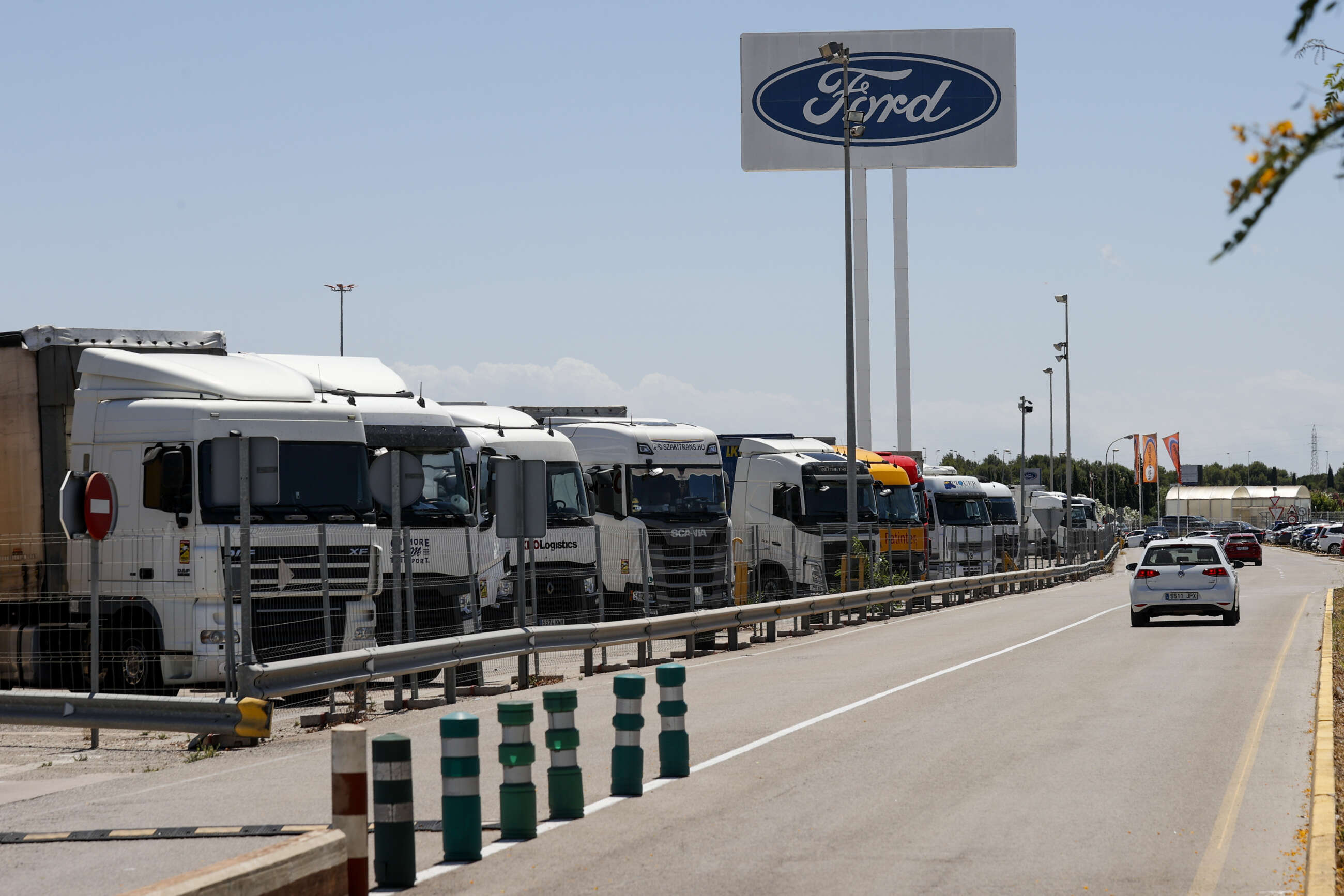 GRAFCVA6725. ALMUSSAFES (VALENCIA), 25/06/2022.- La transformación de la planta española de Ford en una factoría eléctrica con dos modelos de nueva generación requerirá la recualificación de los trabajadores para dominar los nuevos procesos de producción y sus tecnologías y una plantilla más reducida, que comenzará a sufrir los efectos de la transformación con la desaparición de tres de sus cuatro referencias actuales en los próximos dos años. En la imagen numerosos camiones de proveedores aparcados en la factoría de Almussafes. EFE/Manuel Bruque