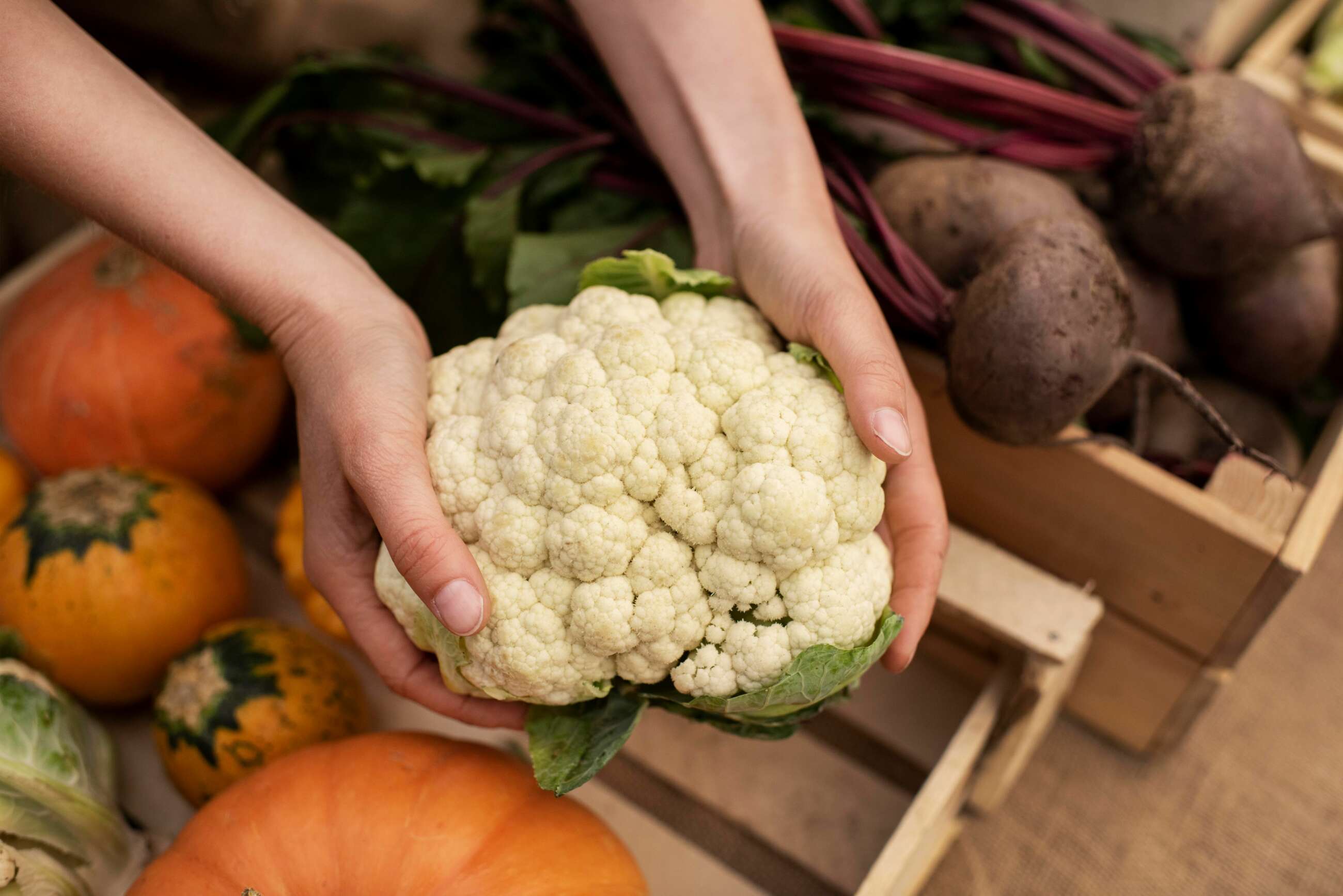 Una persona sostiene una coliflor. Foto: Freepik.