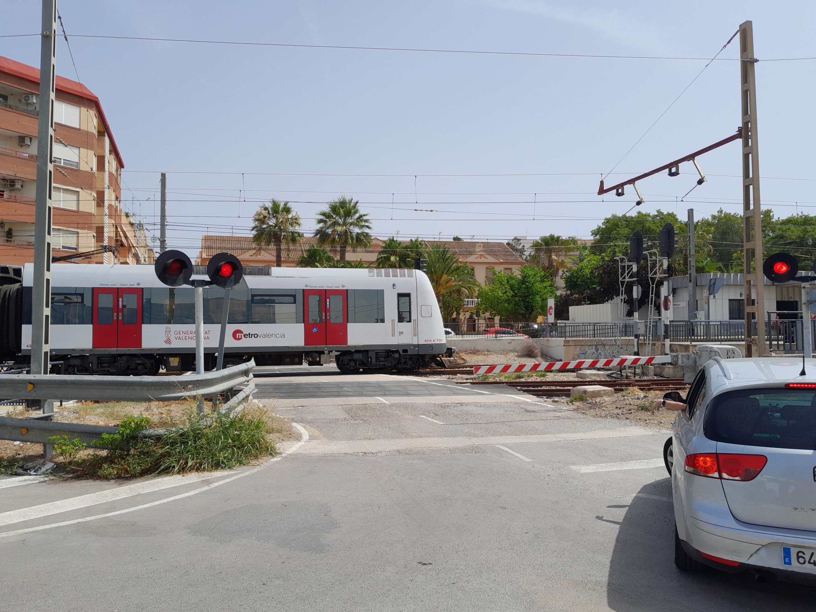 Un cruce de vías en la que aparece un coche y un metro de Metrovalencia en la localidad de Paterna (Valencia)