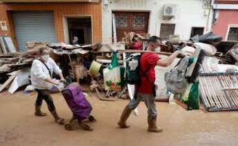 Persones caminant per un carrer de Paiporta arrasat per la DANA