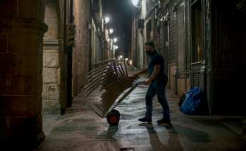 Un hombre recoge las sillas de una terraza / EFE