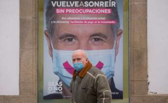 Un hombre con mascarilla pasa frente a un cartel publicitario en Lugo, tras el levantamiento del cierre perimetral de la ciudad, en Lugo, Galicia (España), a 30 de diciembre de 2020. Lugo y Ourense serán las dos únicas urbes gallegas sin cierre - Carlos Castro