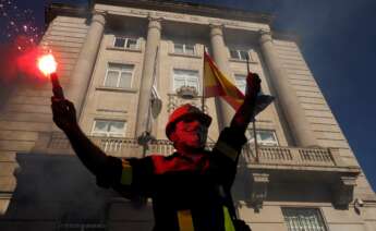 Un manifestante con una bengala delante de la subdelegación del Gobierno, durante la protesta convocada por los trabajadores de Alcoa San Cibrao por la viabilidad de la única fábrica de aluminio primario que queda en España bajo el lema 'A loita continúa'. EFE/Eliseo Trigo