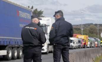 Dos agentes de Policía Nacional observan los camiones parados en el arcén en uno de los accesos al Polígono de O Ceao. Foto: Europa Press