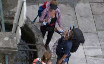 Tres peregrinas beben agua en una fuente en Santiago de Compostela