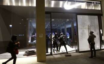 Varios encapuchados entran en un comercio de Barcelona tras la manifestación celebrada esta tarde en protesta por el encarcelamiento del rapero Pablo Hasél. EFE/Quique García