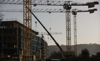 BERANGO (BIZKAIA), 21/09/2022.- Varias grúas se alzan este miércoles sobre un edificio de viviendas en construcción en Berango (Bizkaia), este miércoles, jornada en la que el Instituto Nacional de Estadística (INE) ha publicado los datos de compraventa de vivienda, que aumentó un 8 % en julio, respecto al mismo mes del año pasado, con 53.720 operaciones realizadas, debido al tirón de las ventas de vivienda usada, que crecieron un 10,4 %, mientras que las de obra nueva bajaron un 2,5 %, tras veinte meses consecutivos al alza. EFE/Miguel Toña