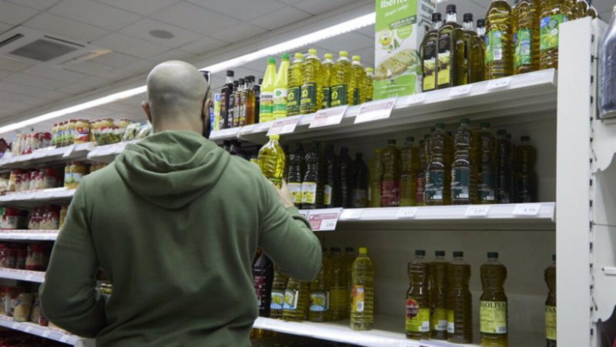 Una persona compra aceite en un supermercado.